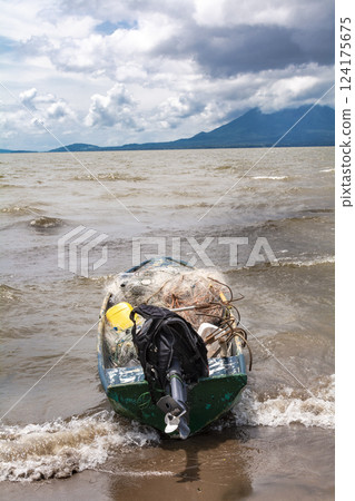 Fishing boat on the shore of a lake. A fishing boat on the shore of a lake with volcanoes in the background. A fishing boat on a lake in Nicaragua. Concept of fishing boats parked at the seaside Fishing boat on the shore of a lake. A fishing boat on the shore of a lake with volcanoes in the background. A fishing boat on a lake in Nicaragua. Concept of fishing boats parked at the seaside 124175675