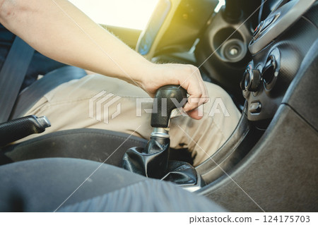 Close-up of driver hand on the gear lever of a car, Driver hand grabbing car gear stick, closeup of hands accelerating on gear stick Close-up of driver hand on the gear lever of a car, Driver hand grabbing car gear stick, closeup of hands accelerating on gear stick 124175703