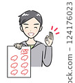 A boy in elementary school smiles and shows a test he got 100 points on 124176023