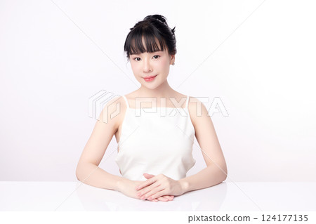 A beautiful young Asian woman with clean, fresh skin against a white background. Skincare, facial treatment, cosmetology, beauty, and spa. An elegant portrait of an Asian woman. 124177135