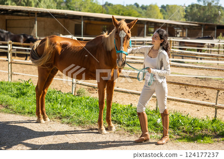 Young woman with horse in paddock 124177237