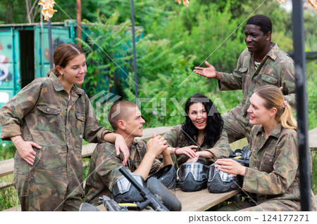 Smiling friends chatting after successful paintball match Smiling friends chatting after successful paintball match 124177271