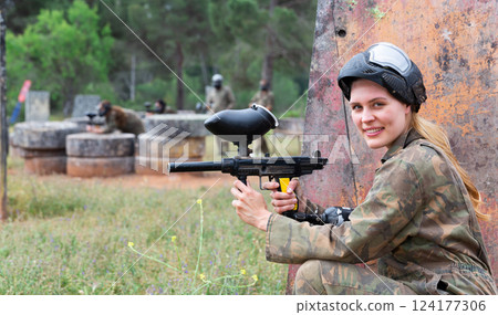 Portrait of girl in camouflage on paintball field 124177306