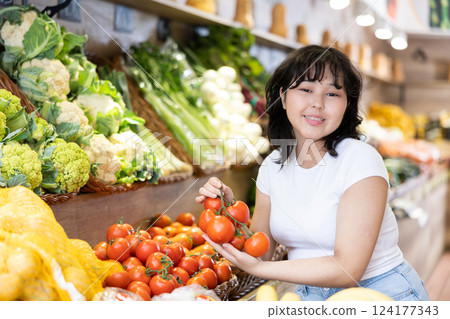 Portrait of positive satisfied girl buying tomatoes in grocery shop Portrait of positive satisfied girl buying tomatoes in grocery shop 124177343