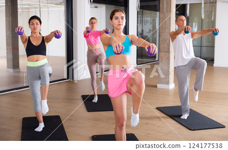 Sports people standing, perform various exercises, holding special small pilates balls in their hands 124177538