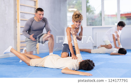Diligent preteen student twisting his opponent's arm on the floor 124177791