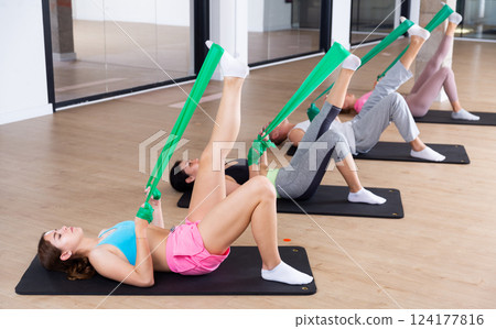 Young adults training pilates with elastic strap 124177816