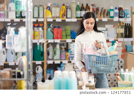 Woman with a full basket of goods and household chemicals in a supermarket 124177851