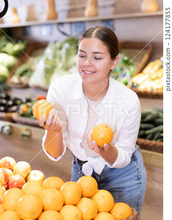 Young girl selecting ripe oranges while shopping in supermarket Young girl selecting ripe oranges while shopping in supermarket 124177855