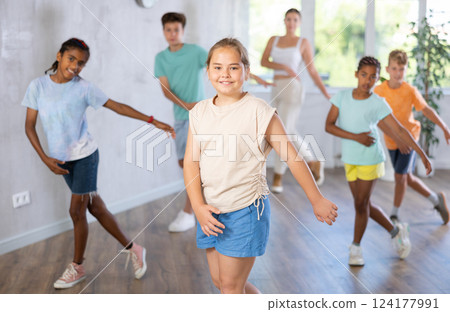 Active preteen girl practicing Hip-hop dance with other children and young trainer 124177991