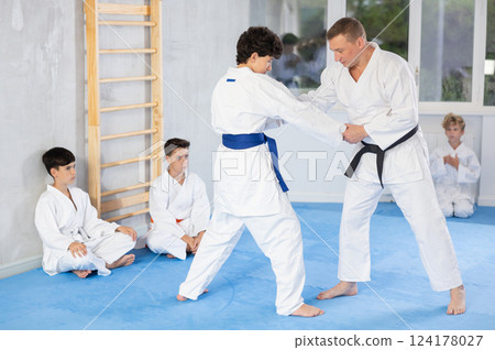 Skilled judo trainer demonstrating wrestling technique on juvenile practitioner Skilled judo trainer demonstrating wrestling technique on juvenile practitioner 124178027