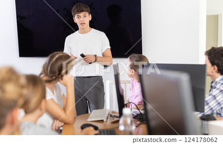 Guy teacher teaches group of students in computer class 124178062