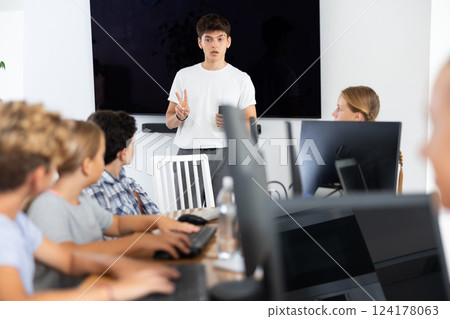 Guy teacher teaches group of students in computer class Guy teacher teaches group of students in computer class 124178063
