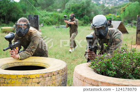 Group of friends paintball players of opposite teams in shootout in forest 124178070
