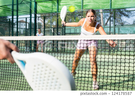Young woman padel tennis player trains on the outdoor court 124178587
