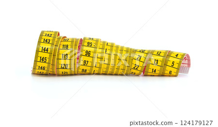 Bright yellow measuring tape coiled on a white surface displays various inch and centimeter markings 124179127