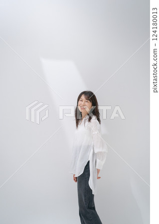 Middle-aged woman standing in front of a white wall 124180013