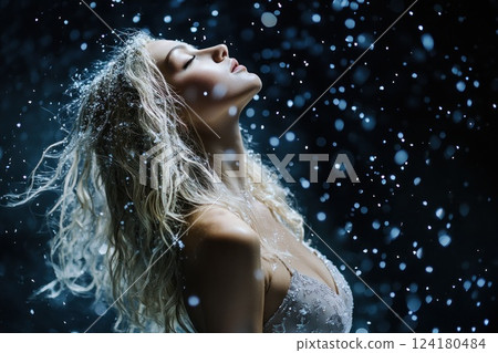 Beautiful blonde woman with long, curly hair in a nightdress standing under a snowfall. Beautiful blonde woman with long, curly hair in a nightdress standing under a snowfall. 124180484
