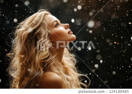Beautiful blonde woman with long, curly hair in a nightdress standing under a snowfall. Beautiful blonde woman with long, curly hair in a nightdress standing under a snowfall. 124180485
