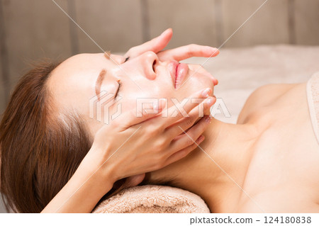 A young Asian woman is getting a facial massage. A young Asian woman is getting a facial massage. 124180838