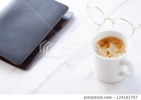 Image of a man working at his desk with a brown leather organizer while drinking a cafe latte, a coffee with milk Image of a man working at his desk with a brown leather organizer while drinking a cafe latte, a coffee with milk 124181707