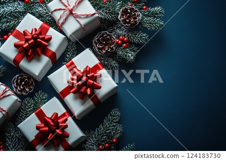 White gift boxes with red bows amid Christmas decorations on dark background 124183730