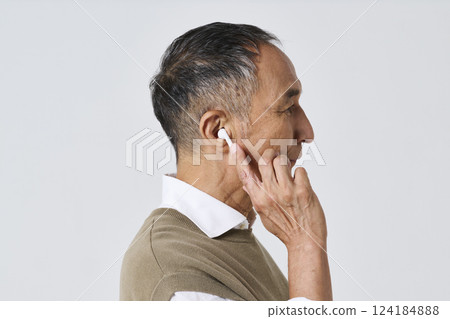 Senior man in casual clothes using wireless earphones Senior man in casual clothes using wireless earphones 124184888