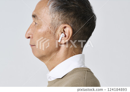 Senior man in casual clothes using wireless earphones 124184893