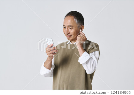 Senior man in casual clothes listening to music on his smartphone 124184905