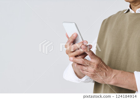 一位穿著休閒服的老人的手正在用智慧型手機 124184914