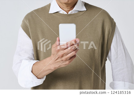The hands of a senior man in casual clothes using a smartphone 124185316