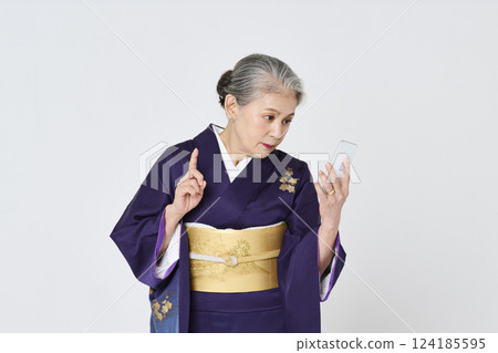Senior woman in purple kimono using a smartphone 124185595