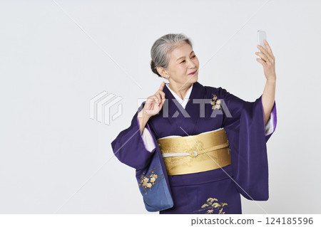 Senior woman in purple kimono taking a selfie with her smartphone Senior woman in purple kimono taking a selfie with her smartphone 124185596