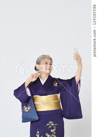 Senior woman in purple kimono taking a selfie with her smartphone 124185598