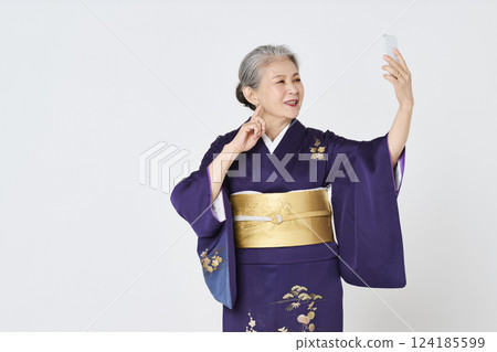 Senior woman in purple kimono taking a selfie with her smartphone 124185599