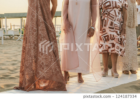 Elegant Women in Dresses Standing on Sandy Beach Elegant Women in Dresses Standing on Sandy Beach 124187334
