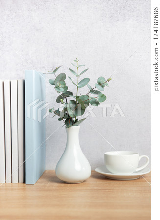 Eucalyptus branches, books, and coffee cup creating a cozy atmosphere on wooden desk 124187686