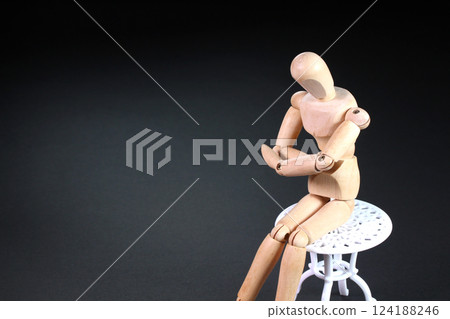 Wooden doll sitting on a chair 124188246