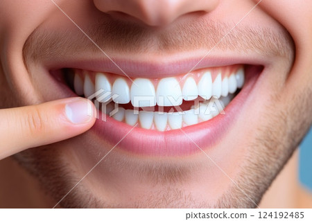 Happy man pointing at his clean white teeth, studio shot Happy man pointing at his clean white teeth, studio shot 124192485