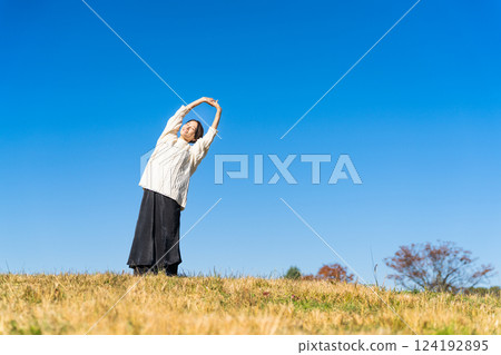 女人在山頂上伸展雙臂的生活方式圖像 女人在山頂上伸展雙臂的生活方式圖像 124192895