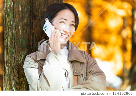 A woman talking on the phone while enjoying the autumn leaves Lifestyle image 124192963