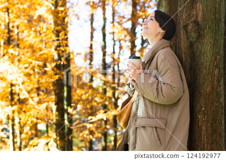 Woman drinking a hot drink while enjoying the autumn leaves Lifestyle image 124192977