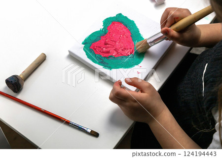 The child paints a red heart 124194443