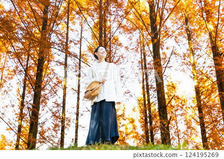A woman strolling through a forest of autumn leaves Lifestyle image A woman strolling through a forest of autumn leaves Lifestyle image 124195269