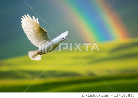 A white dove flies over a mountain range with a rainbow in the sky. 124195935