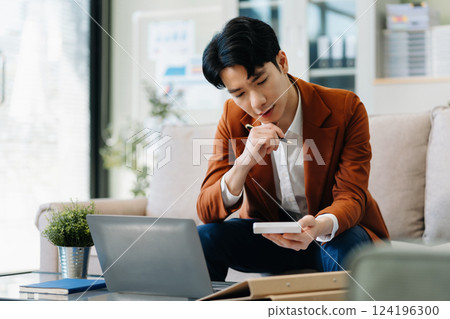 businessman calculate and analyzing graph document financial with report and laptop in office. 124196300