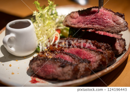 A fork on medium rare wagyu meat served on plate with sauce and vegetable 124196443