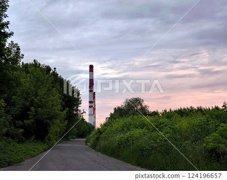 The pipes of the power plant on a country forest road. Evening 124196657
