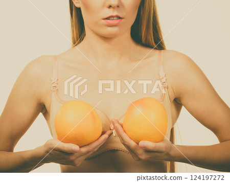 Woman small boobs holds big orange fruits 124197272