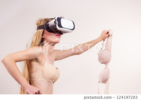 Girl in virtual reality goggles holds bra 124197283